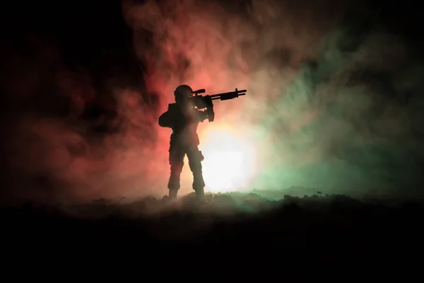Silhueta de atirador militar com arma de precisão em fundo enevoado escuro. tiro, segurando arma, céu colorido, fundo — Fotografia de Stock