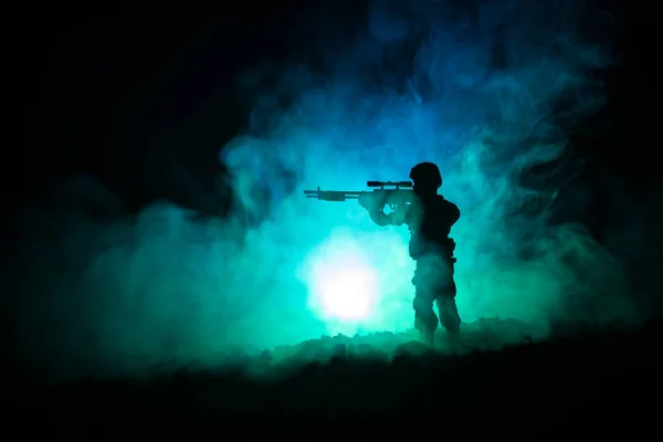 Sziluettjét katonai mesterlövész mesterlövész fegyver: sötét tónusú ködös háttér. lövés, holding a fegyvert, a színes ég, a háttérben — Stock Fotó