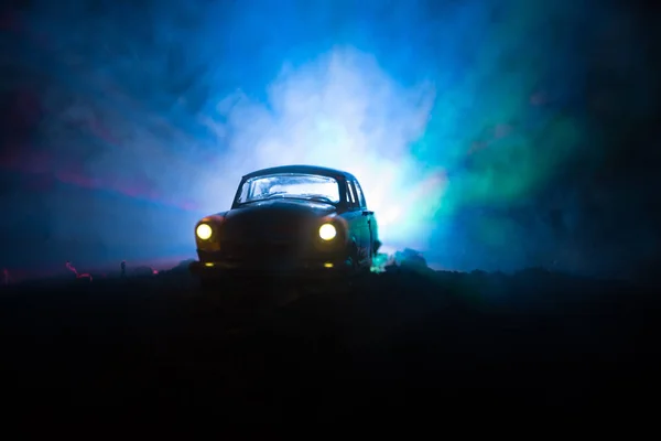 Silhouette de la vieille voiture vintage dans un fond sombre et brumeux avec des lumières incandescentes en basse lumière, ou silhouette de la vieille voiture de crime fond sombre . — Photo