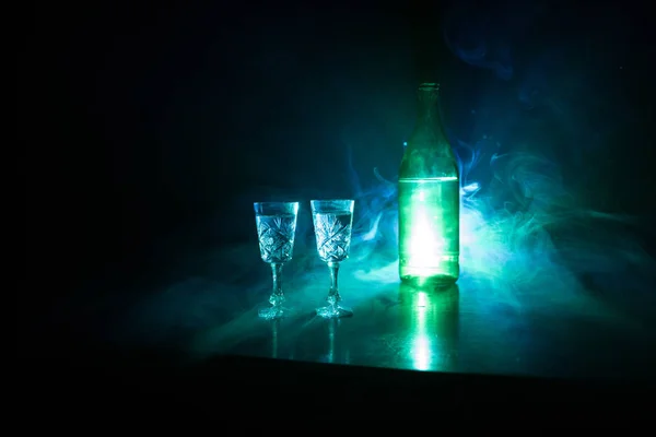 Dois copos de Vodka com garrafa em fundo estilo clube nevoeiro escuro com luzes brilhantes (Laser, Stobe) Multi colorido. Clube bebidas tema decoração. Espaço vazio. — Fotografia de Stock