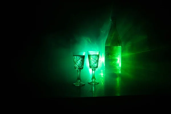 Dois copos de Vodka com garrafa em fundo estilo clube nevoeiro escuro com luzes brilhantes (Laser, Stobe) Multi colorido. Clube bebidas tema decoração. Espaço vazio. — Fotografia de Stock