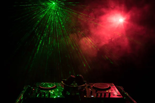DJ dreht, mischt und kratzt in einem Nachtclub, Hände von DJ zwicken verschiedene Trackregler auf dem DJ-Deck, Blitzlicht und Nebel, oder DJ mischt den Track im Nachtclub auf der Party. — Stockfoto