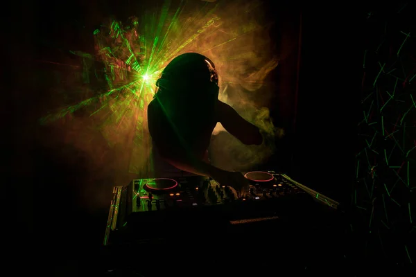 DJ Spinning, Mixing, and Scratching in a Night Club, Manos de dj ajustar varios controles de pista en la cubierta de dj, luces estroboscópicas y niebla, o Dj mezcla la pista en el club nocturno en la fiesta — Foto de Stock