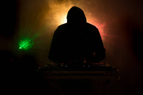 DJ Spinning, Mixing, and Scratching in a Night Club, Hands of dj tweak various track controls on dj's deck, strobe lights and fog, or Dj mixes the track in the nightclub at party