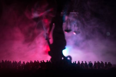 Bulanık dev Bayan adalet heykeli kılıç ve sisli yangın arka plan ile gece kalabalık duran ölçek silüeti. Geceleyin