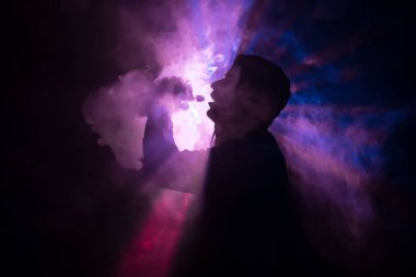 Bir mod tutarak Vaping adam. Buhar bulutu. Siyah arka plan. Vaping elektronik sigara duman bir sürü ile. Vape kavramı