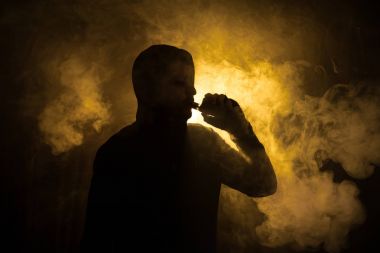Bir mod tutarak Vaping adam. Buhar bulutu. Siyah arka plan. Vaping elektronik sigara duman bir sürü ile. Vape kavramı
