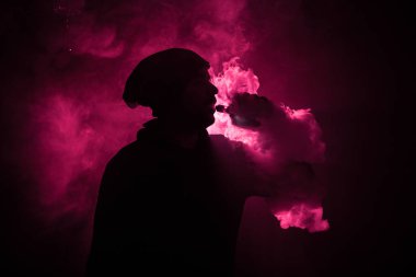 Bir mod tutarak Vaping adam. Buhar bulutu. Siyah arka plan. Vaping elektronik sigara duman bir sürü ile. Vape kavramı