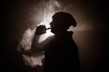 Bir mod tutarak Vaping adam. Buhar bulutu. Siyah arka plan. Vaping elektronik sigara duman bir sürü ile. Vape kavramı