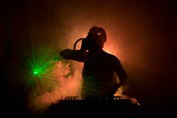 DJ dreht, mischt und kratzt in einem Nachtclub, Hände von DJ zwicken verschiedene Trackregler auf dem DJ-Deck, Blitzlicht und Nebel, oder DJ mischt den Track im Nachtclub auf der Party — Stockfoto