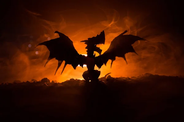 Silhouette of fire breathing dragon with big wings on a dark orange background — Stock Photo, Image