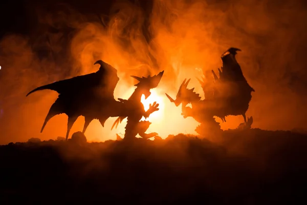 Silhouette of fire breathing dragon with big wings on a dark orange background — Stock Photo, Image