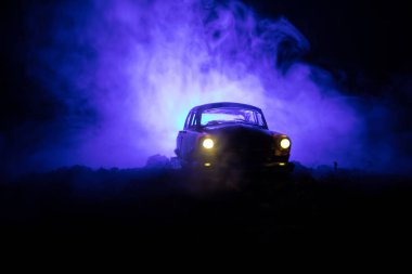 Eski model araba sisli karanlıkta parlayan ışıklar ile arka plan tonda siluet eski ışık yetersiz veya eski siluet suç araba koyu arka plan.