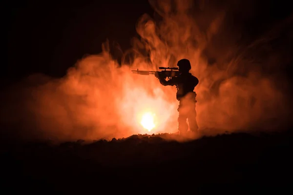 Silhueta de atirador militar com arma de precisão em fundo enevoado escuro. tiro, segurando arma, céu colorido, fundo — Fotografia de Stock