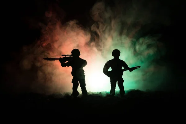 Silhueta de atirador militar com arma de precisão em fundo enevoado escuro. tiro, segurando arma, céu colorido, fundo — Fotografia de Stock