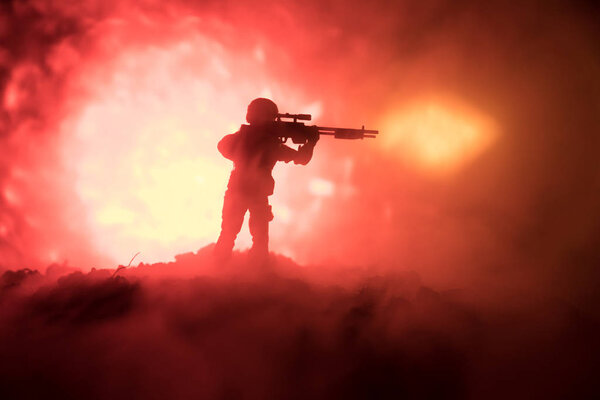 Армейский снайпер с крупнокалиберной снайперской винтовкой ищет убийцу врага. Силуэт на фоне неба. Национальная безопасность обеспечена, военнослужащие на страже
