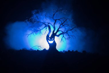 Karanlık sisli yüzündeki korku korkunç Cadılar Bayramı ağacıyla silüeti arka plan arka yüzü aya ile tonda. Zombi ve şeytan yüzü olan korkunç korku ağaç.