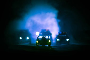 Sis arka plan ile gece bir Ford Thunderbird araba kovalayan oyuncak Bmw polis ve Toyota Fj Cruiser arabalar. Oyuncak dekorasyon sahne masada. - 11 Ocak 2018, Bakü Azerbaycan