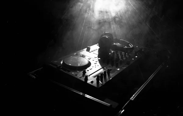 DJ Spinning, Mixing, and Scratching in a Night Club, Manos de dj ajustar varios controles de pista en la cubierta de dj, luces estroboscópicas y niebla, o Dj mezcla la pista en el club nocturno en la fiesta — Foto de Stock