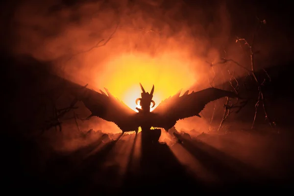Silhouette of fire breathing dragon with big wings on a dark orange background. Horror image — Stock Photo, Image
