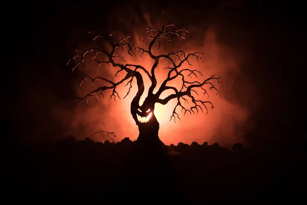 Silhouette di spaventoso albero di Halloween con volto horror su sfondo scuro nebbioso tonica con la luna sul retro. Spaventoso albero dell'orrore con zombie e demoni volti . — Foto Stock