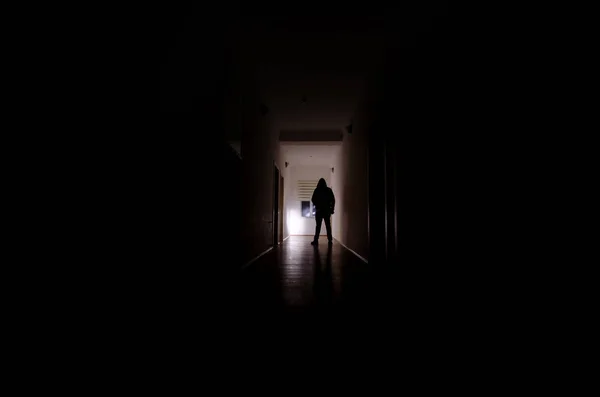 Σκοτεινός διάδρομος με πόρτες γραφείων και τα φώτα με τη σιλουέτα του τρόμου στοιχειωμένος άνθρωπος στέκεται με διαφορετικές πόζες. — Φωτογραφία Αρχείου