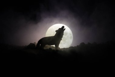 Siluet karanlık karşı uluyan kurt sisli arka plan ve dolunay ya da kurt tam aya inleyen siluet tonda. Halloween korku kavramı.