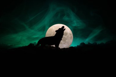 Siluet karanlık karşı uluyan kurt sisli arka plan ve dolunay ya da kurt tam aya inleyen siluet tonda. Halloween korku kavramı.