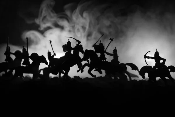 Scène de bataille médiévale avec cavalerie et infanterie. Silhouettes de figures comme objets séparés, lutte entre guerriers sur fond brumeux foncé. Scène nocturne . — Photo