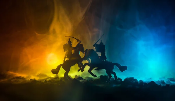 Middeleeuwse slag scène met de cavalerie en infanterie. Silhouetten van figuren als afzonderlijke objecten, strijd tussen krijgers op donker getinte mistige achtergrond. Nachtbeeld. — Stockfoto