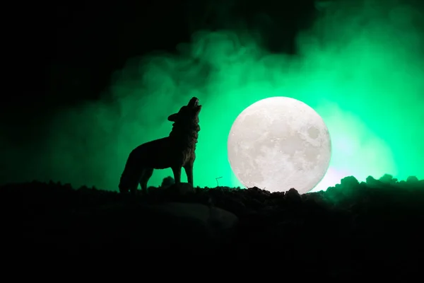 Silhouet van huilende wolf tegen donker getinte mistige achtergrond en volle maan of Wolf in silhouet huilend naar de volle maan. Halloween horror concept. — Stockfoto