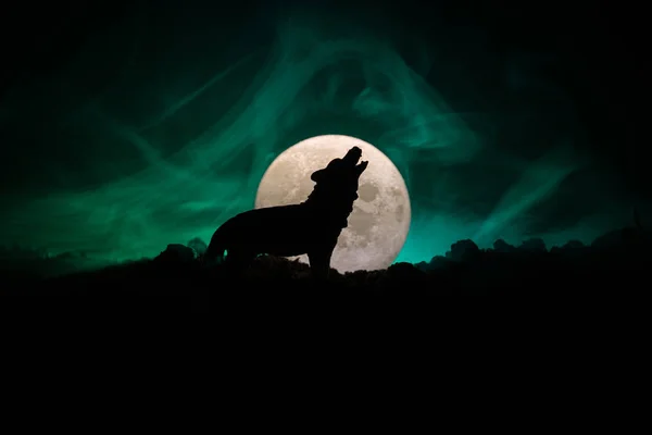 Silhueta de lobo uivante contra fundo enevoado escuro e lua cheia ou lobo em silhueta uivando até a lua cheia. Conceito de horror Halloween . — Fotografia de Stock