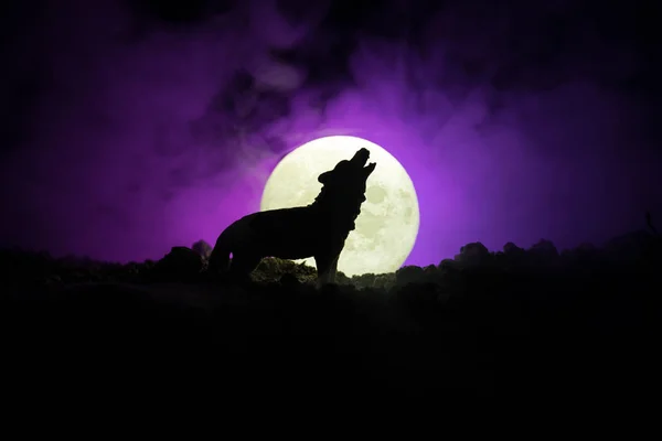 Silhueta de lobo uivante contra fundo enevoado escuro e lua cheia ou lobo em silhueta uivando até a lua cheia. Conceito de horror Halloween . — Fotografia de Stock