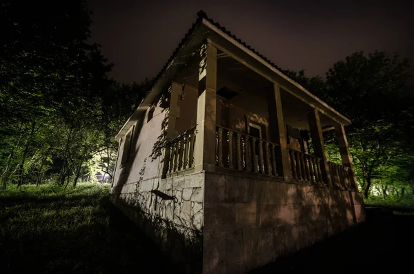 산 안개 달 밤에 숲에서 건물의 밤 풍경입니다. 녹색 초원, 큰 나무와 밤에 버려진된 집. 밤 장면 — 스톡 사진