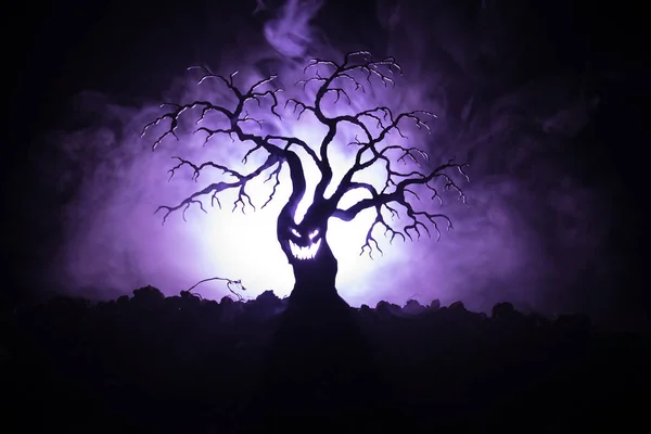 Силуэт пугающего Хэллоуинского дерева с ужасающим лицом на темном туманном фоне с луной на задней стороне. Страшное дерево ужасов с зомби и демоническими лицами . — стоковое фото