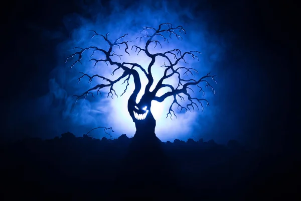 可怕的万圣节树的剪影与恐怖的脸在黑暗的雾色调背景与月球背面。恐怖恐怖树与僵尸和恶魔面孔. — 图库照片