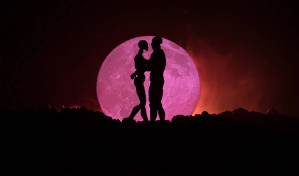 Silueta de pareja besándose bajo luna llena. Chico beso chica mano en luna llena silueta fondo. Concepto de decoración del día de San Valentín. Silueta de pareja amorosa besándose contra la luna — Foto de Stock