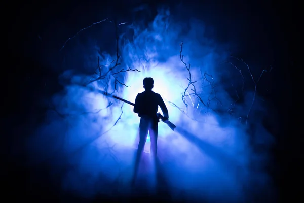 Man with riffle at spooky forest at night with light, or War Concept. Military silhouettes fighting scene on war fog sky background, World War Soldier Silhouette Below Cloudy Skyline At night. — Stock Photo, Image