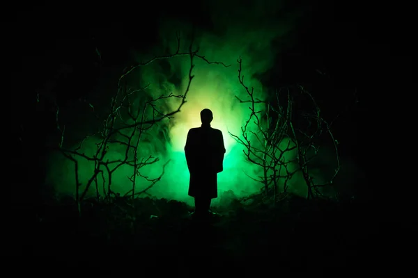 Extraña silueta en un oscuro bosque espeluznante por la noche, luces surrealistas paisaje místico con hombre espeluznante. Tonificado — Foto de Stock