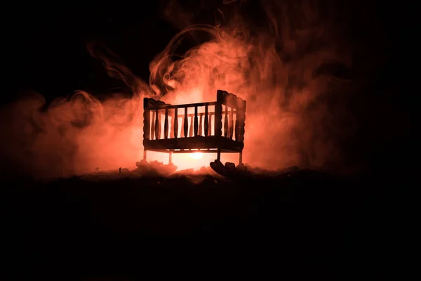 Vecchio inquietante culla inquietante bambino in legno in sfondo scuro nebbioso tonica. Concetto di orrore. Spaventoso bambino e letto silhouette nel buio — Foto Stock