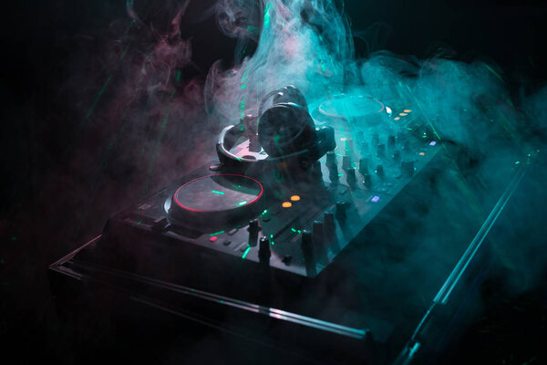 DJ Spinning, Mixing, and Scratching in a Night Club, Hands of dj tweak various track controls on dj's deck, strobe lights and fog, or Dj mixes the track in the nightclub at party
