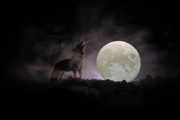 Silhouet van huilende wolf tegen donker getinte mistige achtergrond en volle maan of Wolf in silhouet huilend naar de volle maan. Halloween horror concept. — Stockfoto