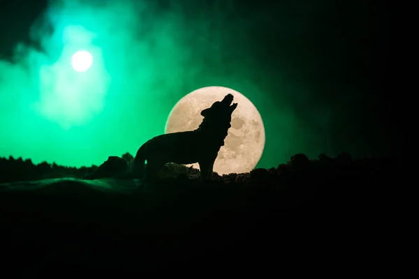 Silhuetten av ylande varg mot mörk tonad dimmig bakgrund och fullmåne eller varg i siluett ylande till fullmånen. Halloween skräck koncept. — Stockfoto