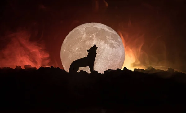 Silhouette eines heulenden Wolfes vor dunkel getöntem Nebelhintergrund und Vollmond oder Wolf in Silhouette, der zum Vollmond heult. Halloween-Horror-Konzept. — Stockfoto