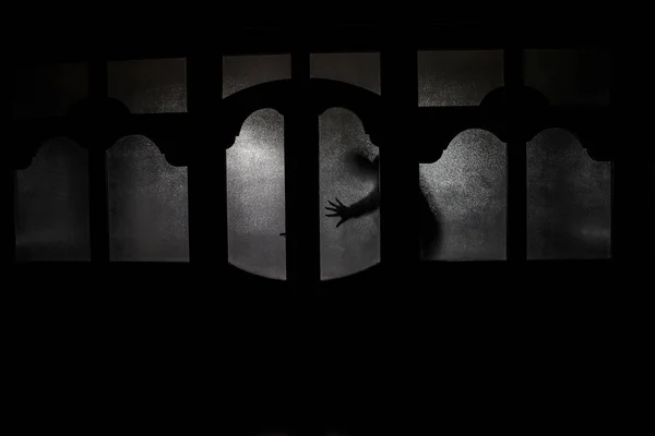 Silhouette d'une silhouette d'ombre inconnue sur une porte à travers une fermeture — Photo