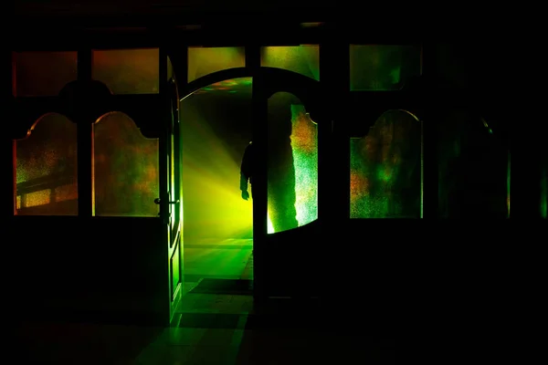 Silhouette of an unknown shadow figure on a door through a closed glass door. The silhouette of a human in front of a window at night. Scary scene halloween concept of blurred silhouette — Stock Photo, Image