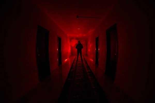 Silueta espeluznante en el oscuro edificio abandonado. Corredor oscuro con puertas de gabinete y luces con silueta de espeluznante persona de horror de pie con diferentes poses . — Foto de Stock