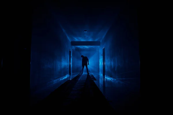 Creepy silhouette in the dark abandoned building. Dark corridor with cabinet doors and lights with silhouette of spooky horror person standing with different poses. — Stock Photo, Image