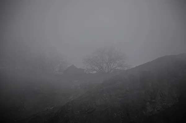 Bellissimo paesaggio di montagne e foreste con edificio del villaggio o vecchia casa di mattoni in rovina abbandonata. Foresta appannata e vecchio edificio — Foto Stock