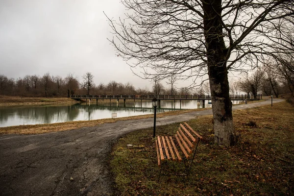 Leere Bank im Park am Teich bei nebligem Tag, minimalistische kalte Jahreszeit Szene. Bank am See im Nebel im Wald. Bank am See bei Nebel. Azerbaidschanische Natur. — Stockfoto